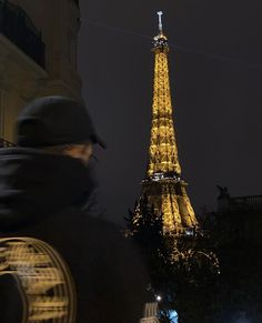 the eiffel tower lit up at night with people walking around in front of it