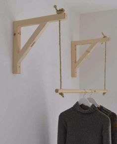 two wooden clothes racks hanging on the wall next to a sweater rack and coat hanger