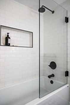 a bathroom with a glass shower door and black faucet handles on the wall