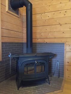 a wood burning stove sitting inside of a wooden room next to a wall covered in planks