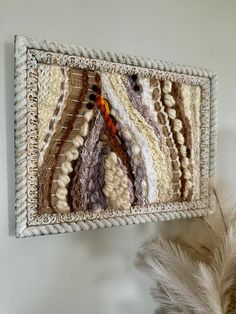 a close up of a wall hanging made out of different types of fabric and beads