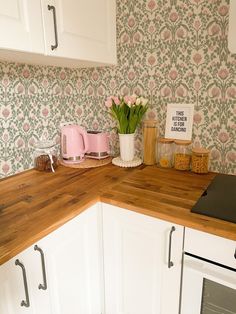 a kitchen counter with flowers on it next to a stove top oven and wall paper