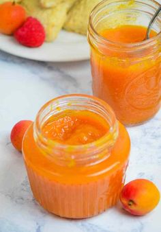 two jars filled with orange juice next to cookies