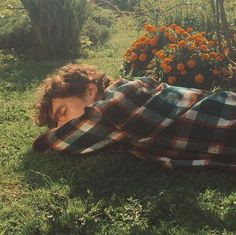 a young boy laying on the grass with his eyes closed and covering himself from the sun