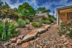 a house with rocks and flowers in front of it