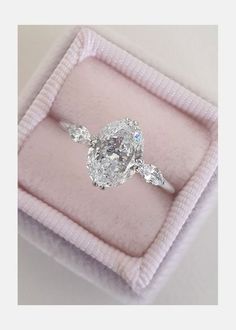 an oval cut diamond ring in a pink velvet gift box with the top section partially open