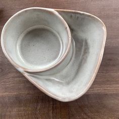 two white bowls sitting on top of a wooden table