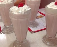 there are three drinks on the table with whipped cream in them and one has a straw