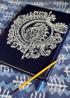 a blue notebook with white designs on it and a yellow pencil laying next to it