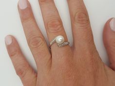 a woman's hand with a pearl and diamond ring on top of her finger