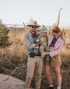 a man and woman standing next to each other in front of an animal statue with a dinosaur on it's head