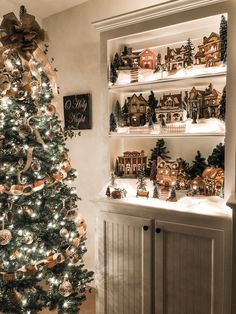 a christmas tree in front of a shelf with ornaments on it