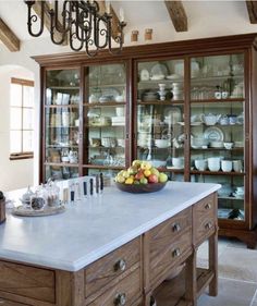 a bowl of fruit on top of a counter in a room with wooden beams and exposed ceiling