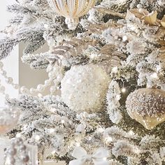 a white christmas tree decorated with gold and silver ornaments