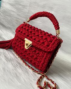 a red crocheted handbag sitting on top of a white furnishing