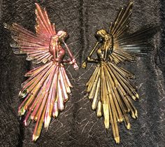 two gold and pink angel brooches sitting on top of a black cloth covered table