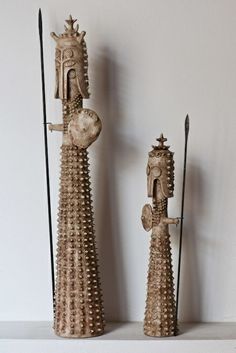 two decorative objects are sitting on a shelf next to each other and one is holding a spear