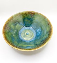 a green and blue bowl sitting on top of a white table