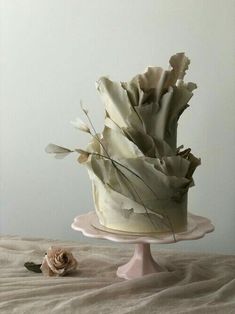 there is a cake with flowers on the top of it and a white wall in the background