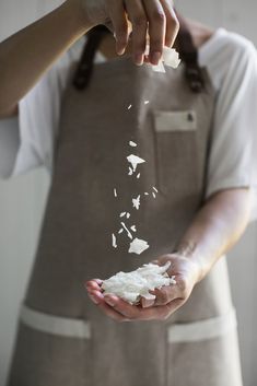 a person in an apron is sprinkled with white sugar on their hands,