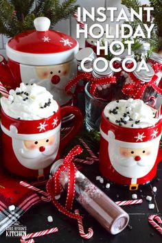 three mugs filled with hot chocolate and whipped cream decorated like santa clause, sitting on top of a table