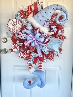 a christmas wreath hanging on the front door with an elephant and candy canes attached to it