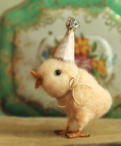 a small bird with a party hat on it's head sitting on a table