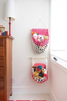 two baskets are hanging on the wall with stuffed animals in them and one is holding toys