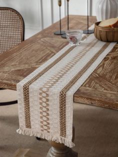 a wooden table topped with a white and brown table runner