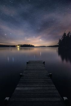 a dock that is sitting in the middle of a body of water under a night sky