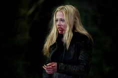 a woman with blood on her face standing in the dark