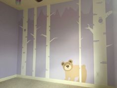 there is a bear and tree mural on the wall in this child's room