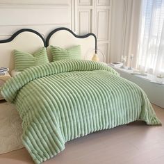 a bed with green bedspread and pillows in a room