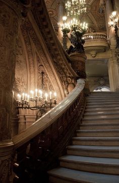 an ornate staircase with chandeliers and candles