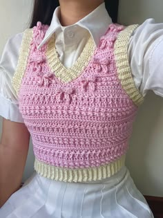 a woman wearing a pink and white top with crocheted details on the chest