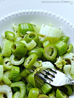 a white bowl filled with green vegetables and a fork on top of the salad is ready to be eaten