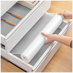 a person holding a roll of paper in front of a drawer