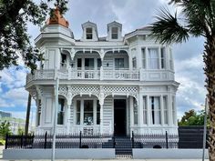 a large white house sitting on the side of a road next to a palm tree