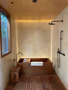 a bathroom with wooden flooring and a bathtub next to a window on the wall