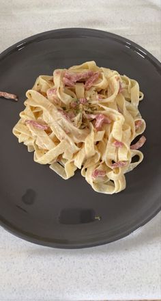 a black plate topped with pasta and ham