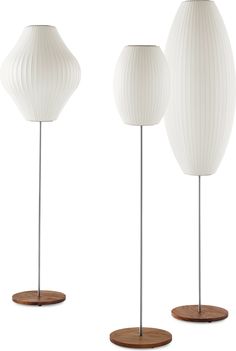 three white vases on wooden bases, one with a round base