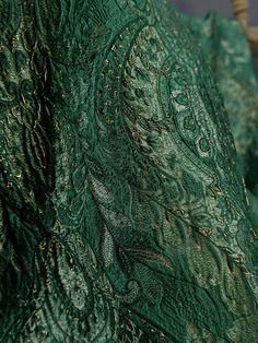 a close up view of the back of a green shawl with intricate designs on it