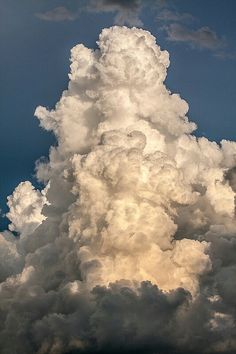 a large cloud is in the sky with some clouds behind it and one plane flying by