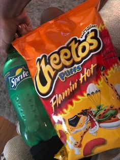 a bag of cheetos sits in someone's lap next to a green bottle