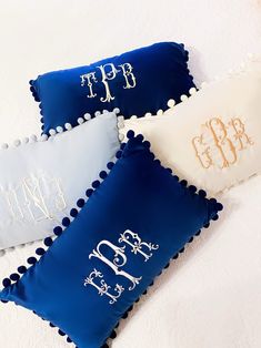 three blue and white decorative pillows with monogrammed letters on the front, one for each pillow