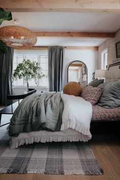 a bed sitting in a bedroom next to a mirror and table with a potted plant on top of it