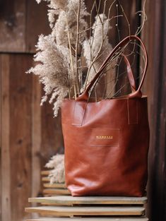 Simple, raw-finished leather bag in a minimalistic style. It is inconspicuous in size but has more than enough room to accommodate your whole world. The bag has a magnetic closure, a small pocket for your smartphone and other essentials, and rolled handle. The bag is both stable and ductile. With time it becomes softer and gets deeper character. The bag size measured in the position presented in the photo is: 35 cm (width), 38 cm (height), 18 cm (depth). When measured laid flat the width amounts Minimalist Brown Bag With Leather Handles, Minimalist Brown Bags With Leather Handles, Everyday Natural Shoulder Bag With Leather Lining, Everyday Natural Leather Shoulder Bag, Natural Leather Shoulder Bag For Everyday Use, Minimalist Leather Shoulder Bag, Vegetable-tanned, Minimalist Vegetable-tanned Leather Shoulder Bag, Natural Leather Lined Everyday Bags, Natural Leather Bags For Gift