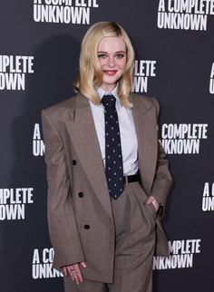 a woman in a suit and tie poses for the camera on the red carpet at an event