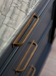 a close up of a door handle on a metal cabinet with marbled surface in the background