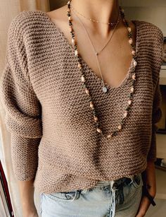 a woman wearing a brown sweater and beaded necklace